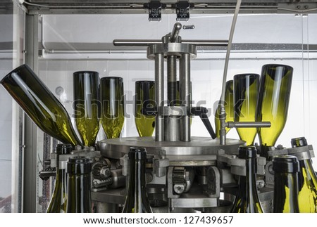Italy, Sicily, wine bottles being washed and filled with wine by an industrial machine in a wine factory