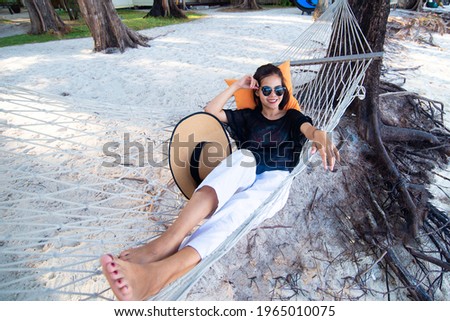 Young Asian woman wearing sunglasses with a pillow resting in comfortable on the hammock at the beach in the sea. The Season of Summer is a relaxation and vacation concept. Travel and holiday. Foto d'archivio © 