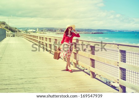 beautiful lady in red walking near the sea in retro style