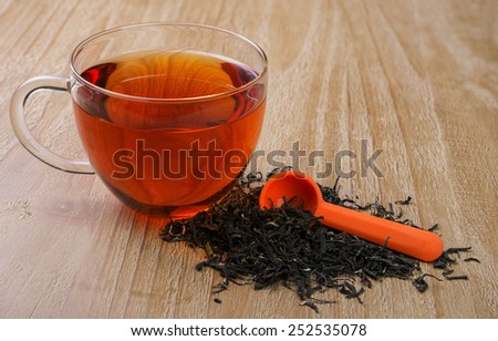 cup of tea and  pile of loose leaf tea on vintage wooden table
