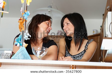 Two brunette women at bar talking and smiling