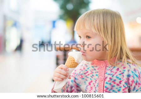Adorable baby eat ice cream sitting on bench in mall