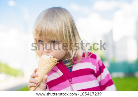 Adorable girl eat ice cream on green grass