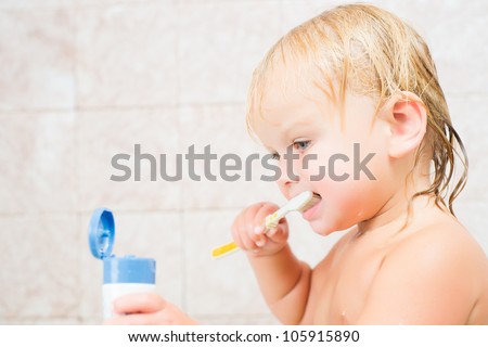Adorable baby brushing teeth staying in bath
