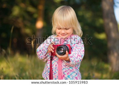 Adorable baby shoot compact camera in park on sunset