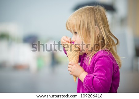 Adorable girl eat ice cream near mall