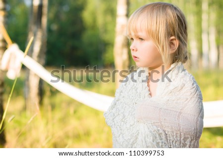 Adorable girl stay covered with white blanket in park