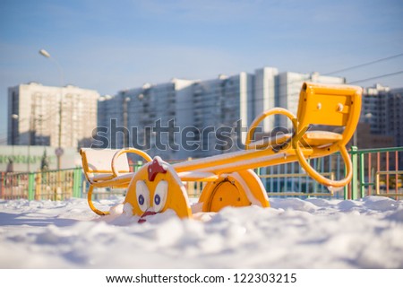 Kids metal swing on winter playground covered with snow