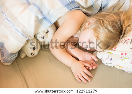 Adorable girl sleep in bed with plush seals toys
