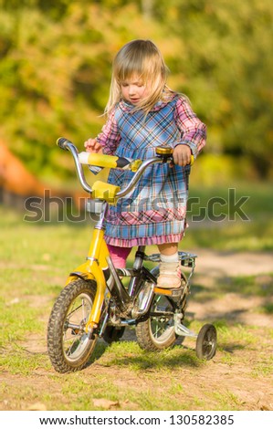 Adorable girl ride on bike with training wheels on playground in park