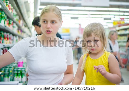 Young mother with daughter select milk drinks in supermarket