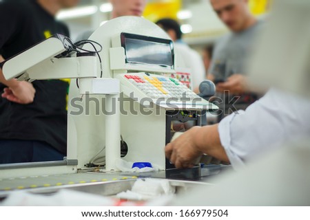 Cashier serves customers  at cash desk in supermarket