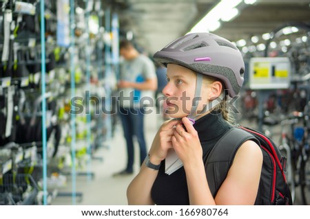 Young woman fitting bike helmet in sport store