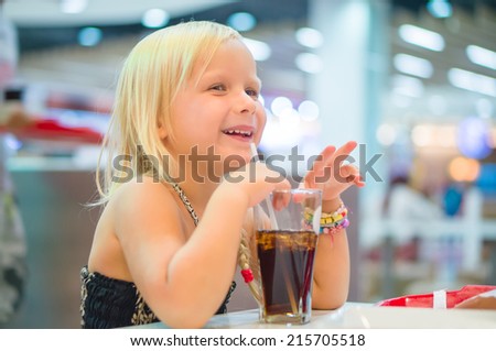 Adorable girl have meal with soda drink and fried potatoes at fast food restaurant