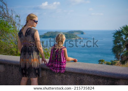 Mother and daughter at side of tropical island view point
