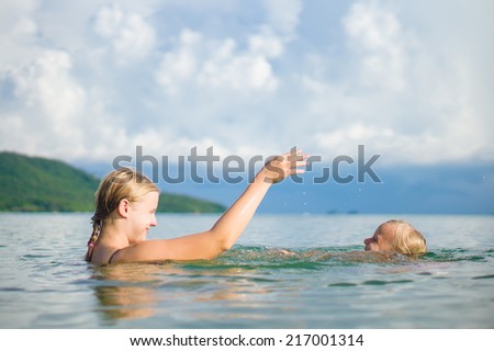 Young mother and daughter have fun swim on island in tropical ocean. Learning swim