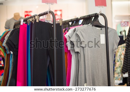 Variety of different color t-shirts and sport trousers on hanger in store