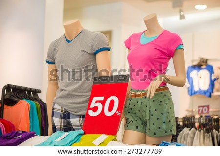 Casual dressed mannequins of man and woman and discount banner in store