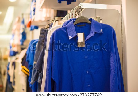 Long sleeve blue color shirts on hangers in clothes store