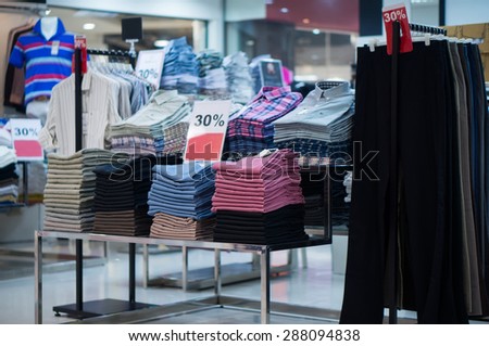 Variety of shirts on hangers and jeans on tables in cloth store