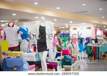 Everyday dressed woman mannequin  with black striped dress and white jacket among cloth on back