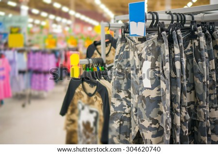 Bunch of military style trousers and t-shirts on hangers in store