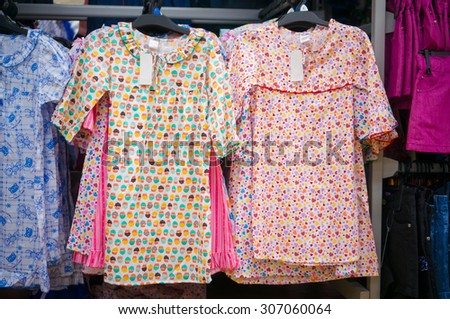 Variety of beautiful baby girl dresses on stands and hangers in supermarket