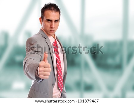 Closeup of a young business man thumb up standing in a light and mordern business hall.