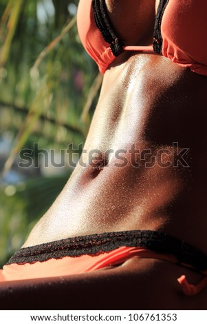 Sexy and fit belly on young woman against the sun