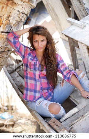 portrait of sexy brunette woman posing in from of shipwreck