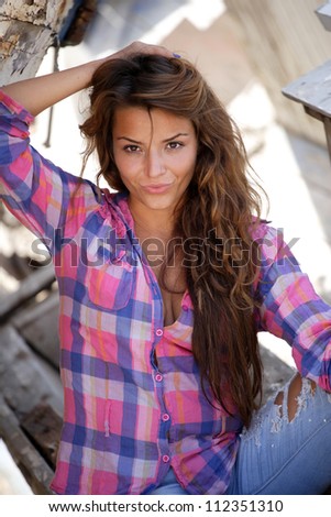 portrait of sexy brunette woman posing in from of shipwreck