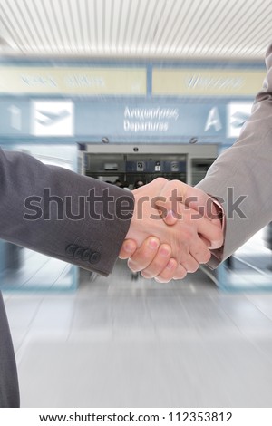 Businessmen shake hands at the airport terminal