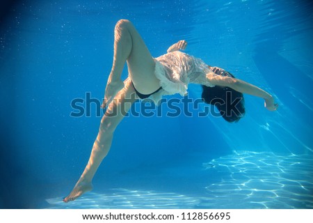 Woman wearing a white dress underwater in swimming pool