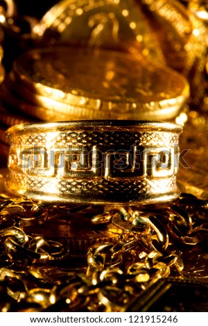 Greek meander ring Jewels and gold coins over dark background