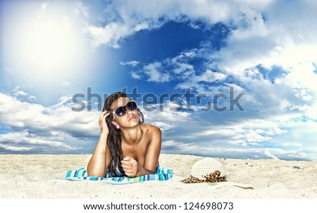 Beautiful young woman in bikini laying on the beach
