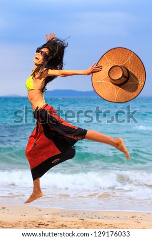 Asian model with hat jumping on the beach in Thailand