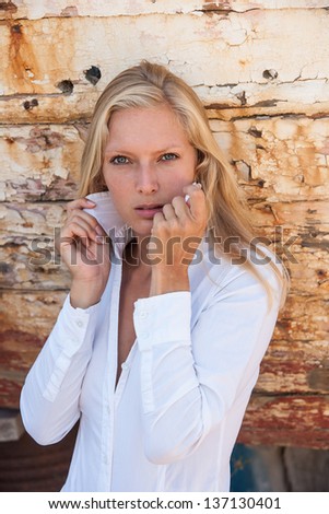 portrait of sexy blonde woman posing in from of shipwreck