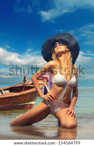 Beautiful woman on the beach with long tail boat in  Thailand.