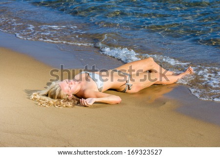 Beautiful young blonde woman in bikini laying on the beach