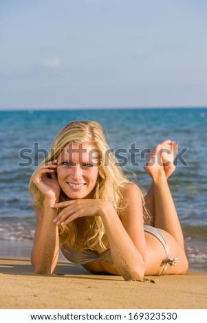 Beautiful young blonde woman in bikini laying on the beach