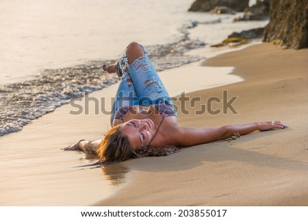 Beautiful woman in bikini top and jeans on the beach. Bali.