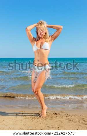 Gorgeous lady in bikini dancing on the beach