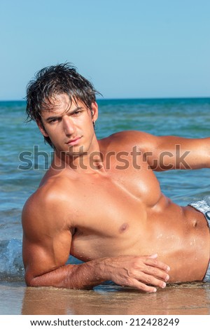Portrait of a handsome young muscular man in swimwear on the beach