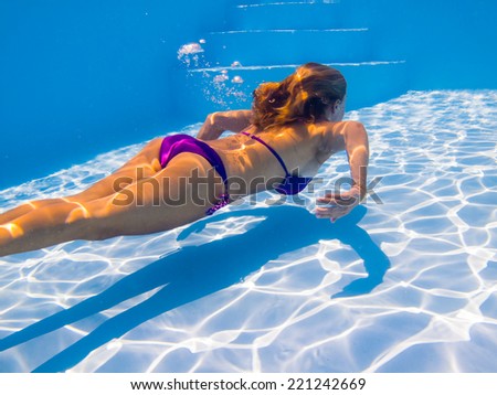 Young woman swimming underwater in the swimming pool