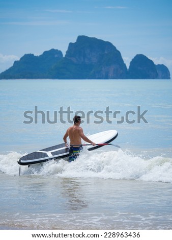 Young man stand up paddle boarding in Thailand on a stormy day