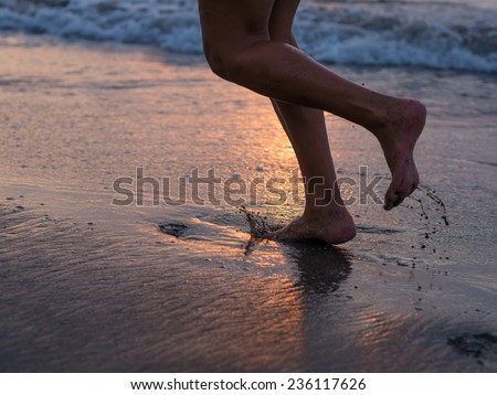 Woman foot on the beach splashing water