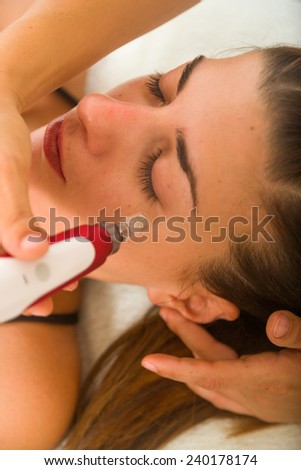Attractive female patient receiving electro acupuncture on face as part of a anti-aging beauty treatment