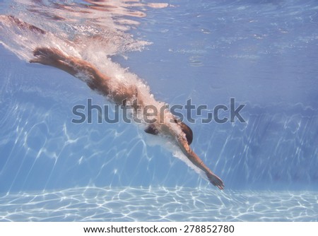 female swimmer after jumping with air bubbles trail in blue water
