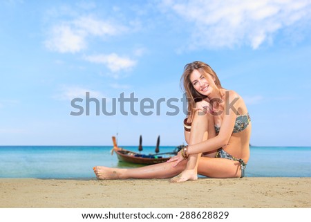 Beautiful young woman in bikini laying on the beach with lon tail boat on background
