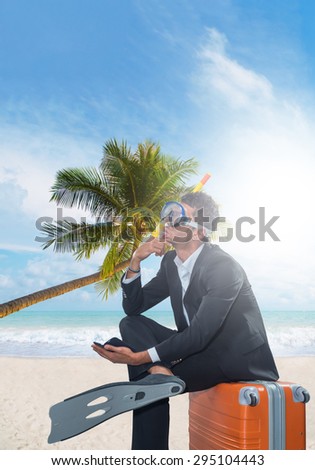 Man in suit sitting on a suitcase at the tropical beach
